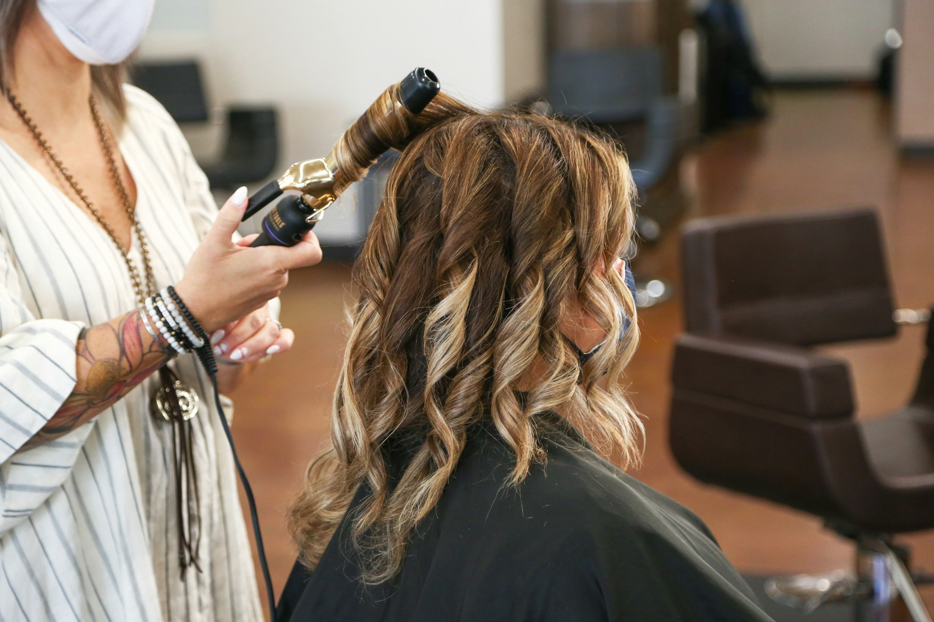 Odoo for Salons woman in stripped shirt curling a customer's hair